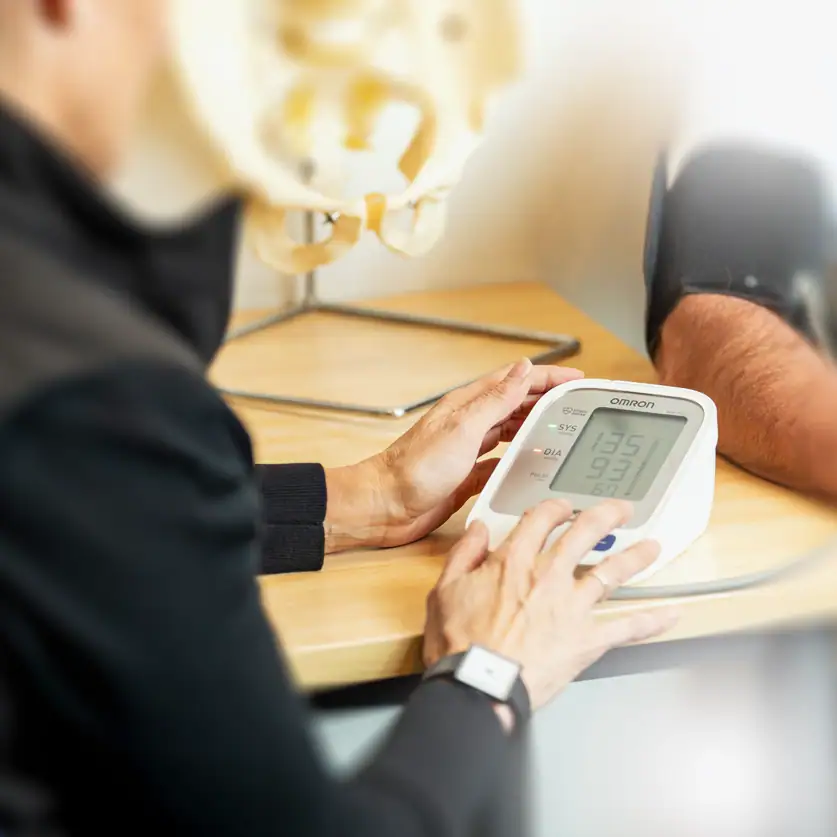 Blood pressure check during a health assessment at Rehab Co clinic.