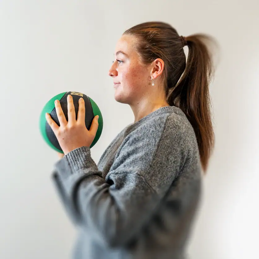 Woman exercising with a medicine ball for physical therapy or fitness.