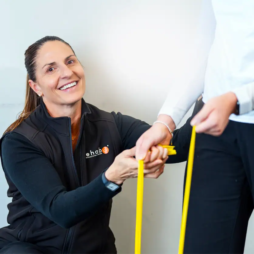 Physiotherapist assisting patient with resistance band exercises.