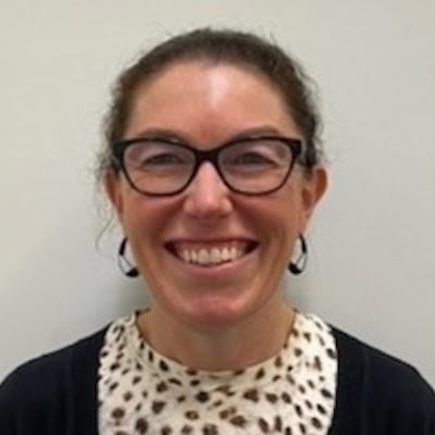 Rehab Co team member smiling, wearing glasses and a patterned top.