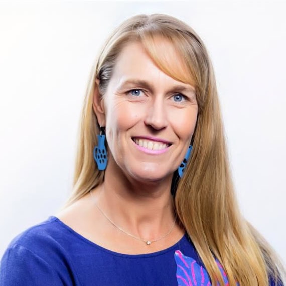 Portrait of Trudi Thomson, smiling woman with blonde hair and blue earrings.