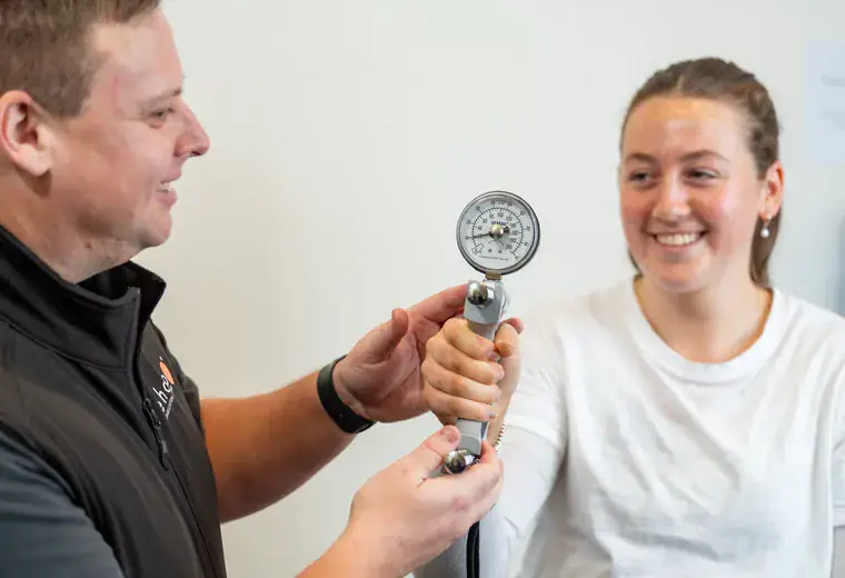 A RehabCo clinician measuring grip strength with a hand dynamometer
