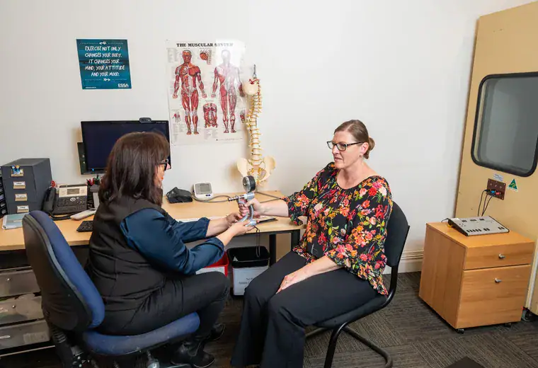 A RehabCo clinician assessing a worker at their desk in the workplace