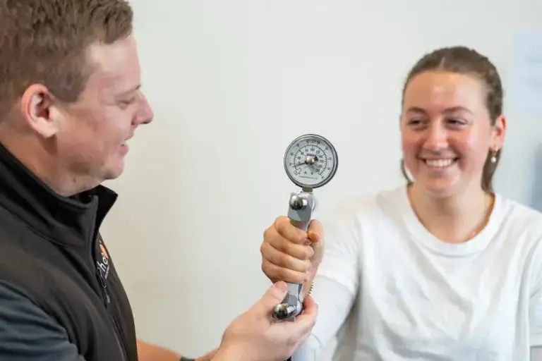 RehabCo clinician measuring grip strength with a hand dynamometer