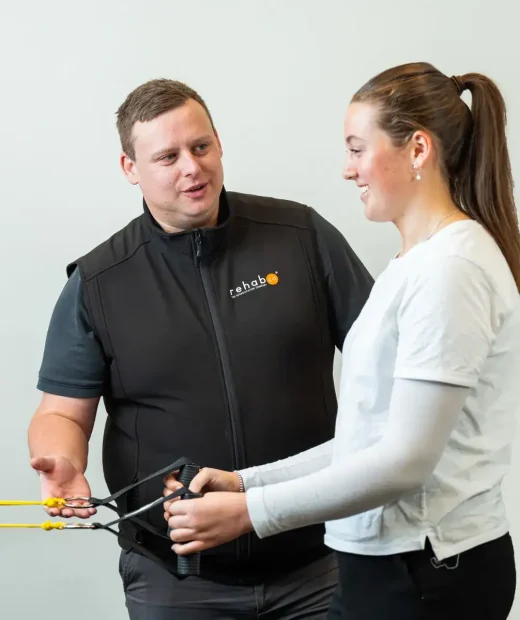 RehabCo exercise physiologist guiding a client through resistance band exercises